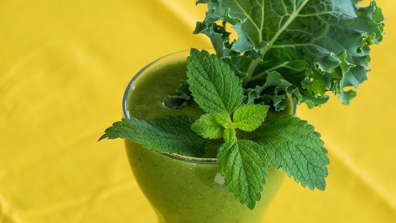 Verre de jus vert avec feuilles de menthe sur fond jaune