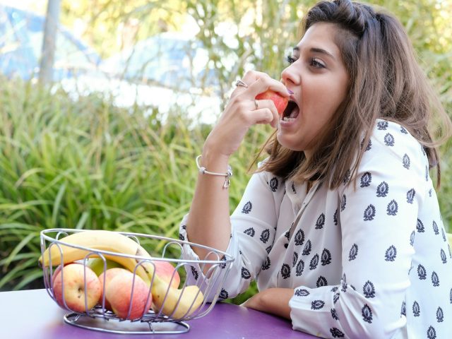 Femme qui mange des fruits frais a une table en plein air