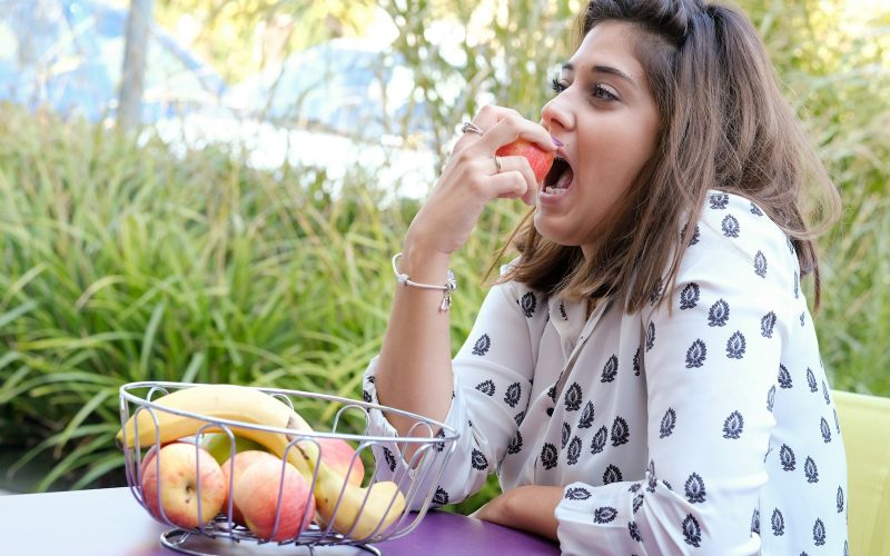 Femme qui mange des fruits frais a une table en plein air