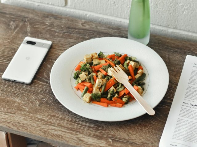 Assiette de salade composee avec telephone et magazine a cote