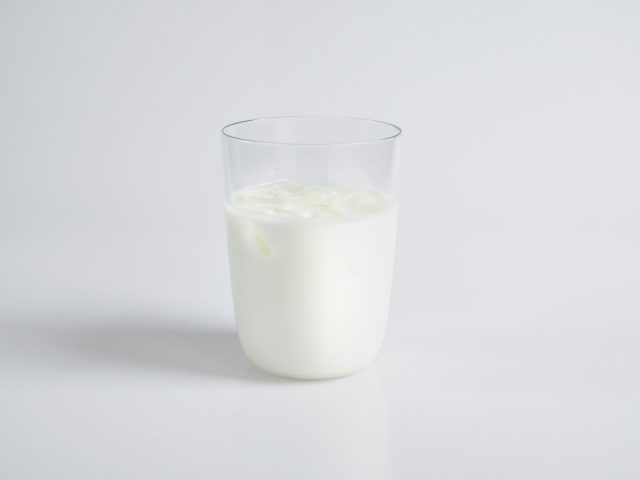 Verre de lait plein sur fond clair