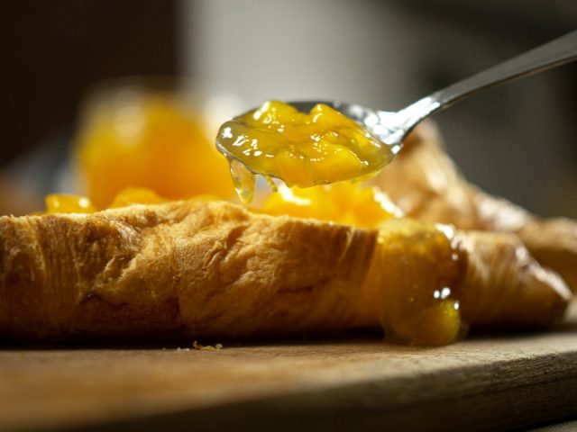 Confiture etalee a la cuillere sur un croissant dore