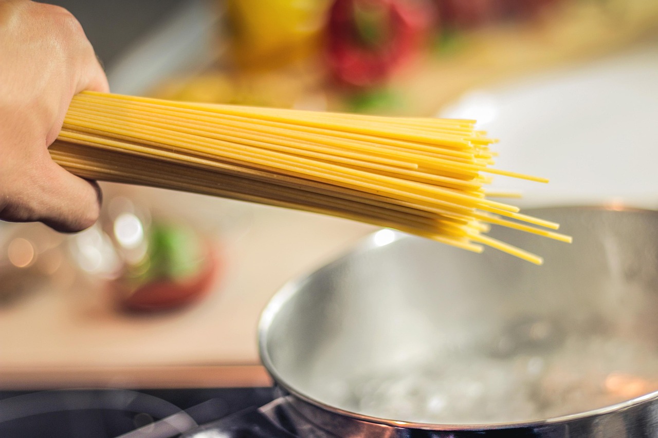 Spaghettis crus tenus au-dessus d'une casserole, avant leur cuisson