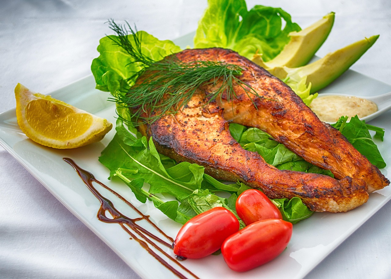 Filet de poisson grillé servi avec avocat, tomates cerises et citron